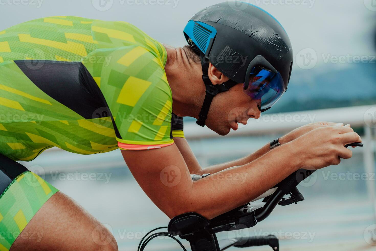 Close up photo of an active triathlete in sportswear and with a protective helmet riding a bicycle. Selective focus