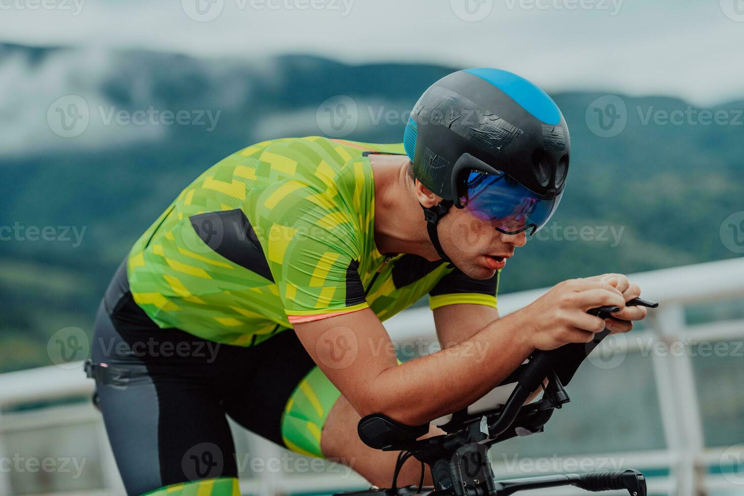 Close up photo of an active triathlete in sportswear and with a protective helmet riding a bicycle. Selective focus