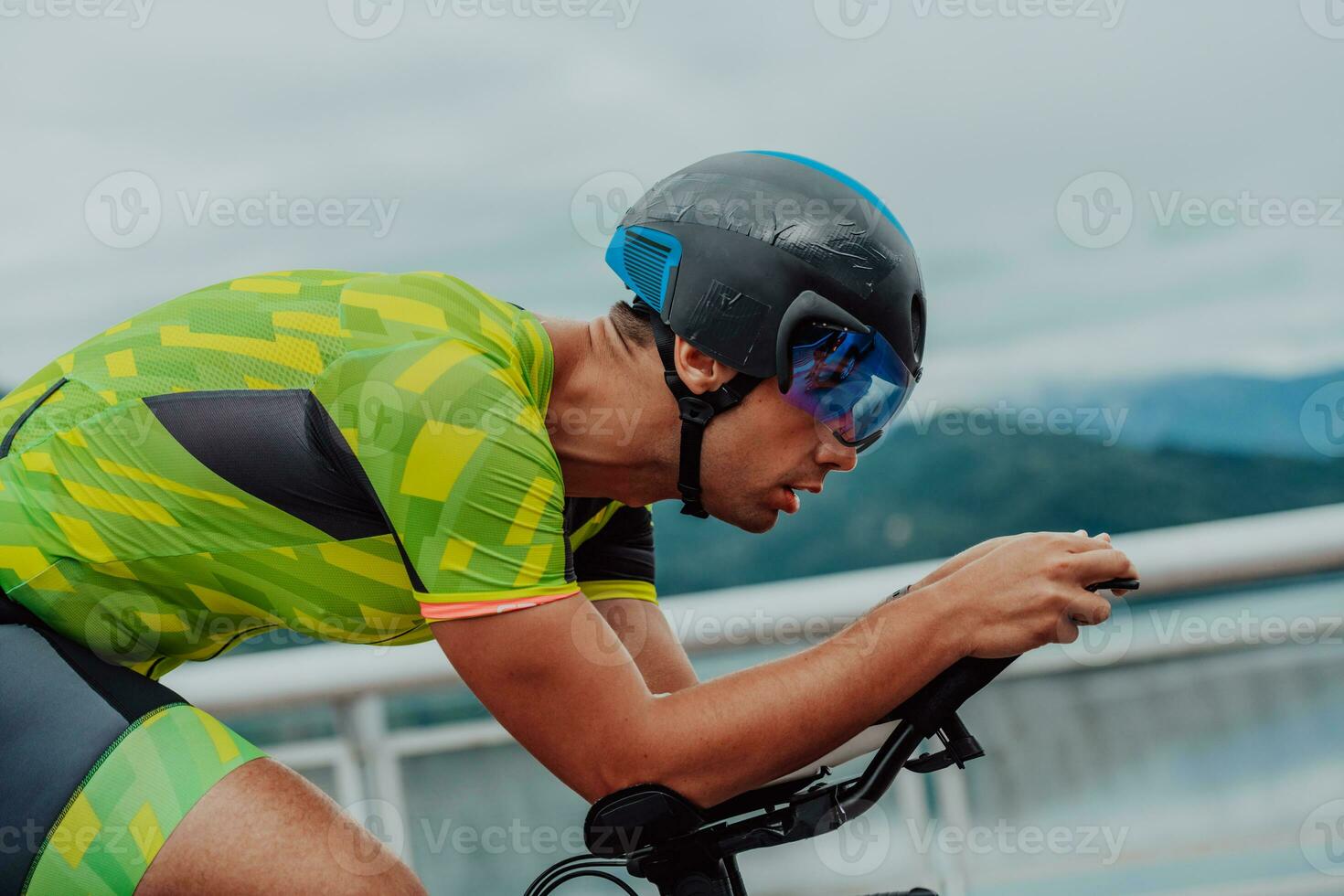 Close up photo of an active triathlete in sportswear and with a protective helmet riding a bicycle. Selective focus