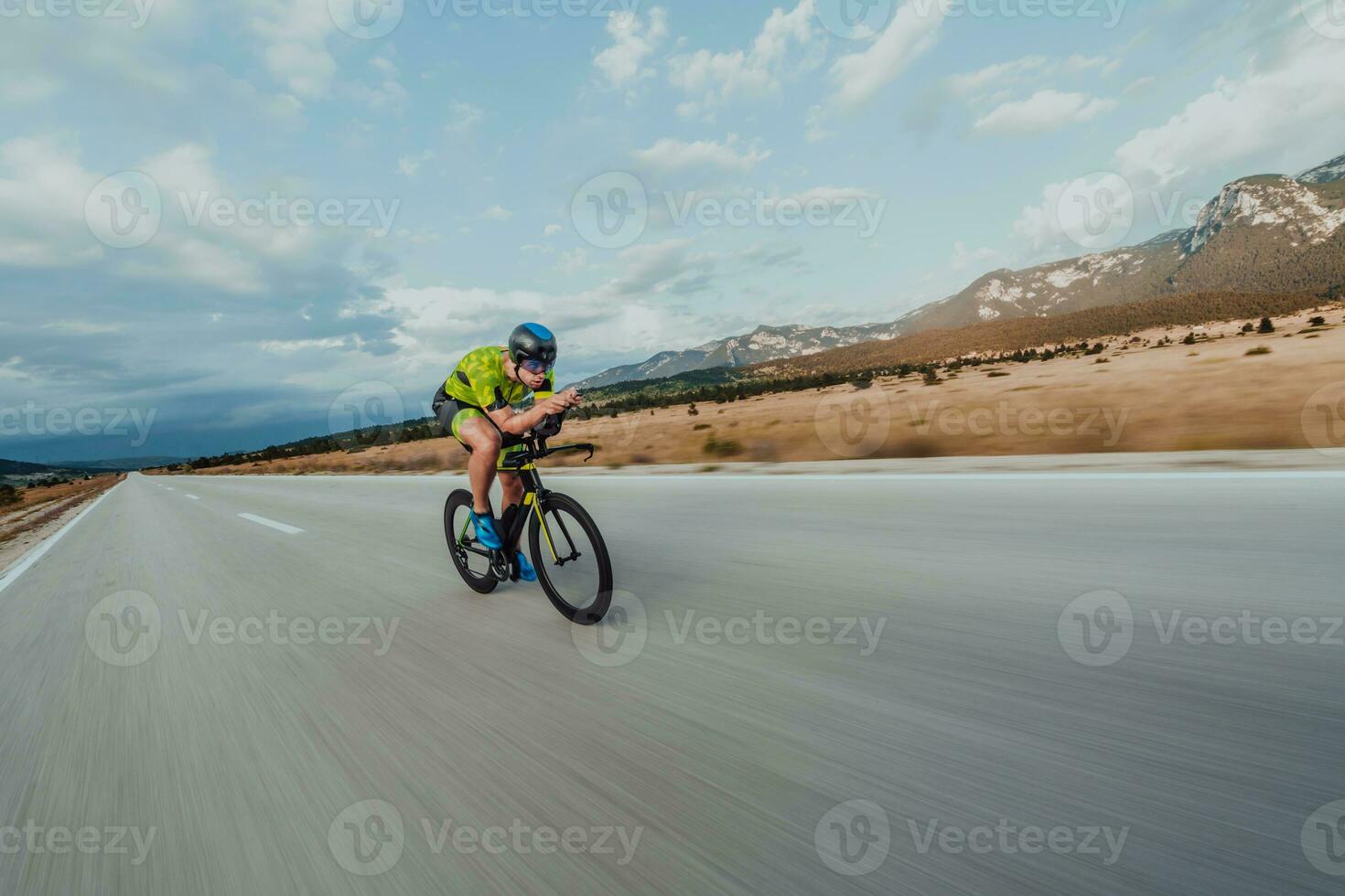 Full length portrait of an active triathlete in sportswear and with a protective helmet riding a bicycle. Selective focus photo