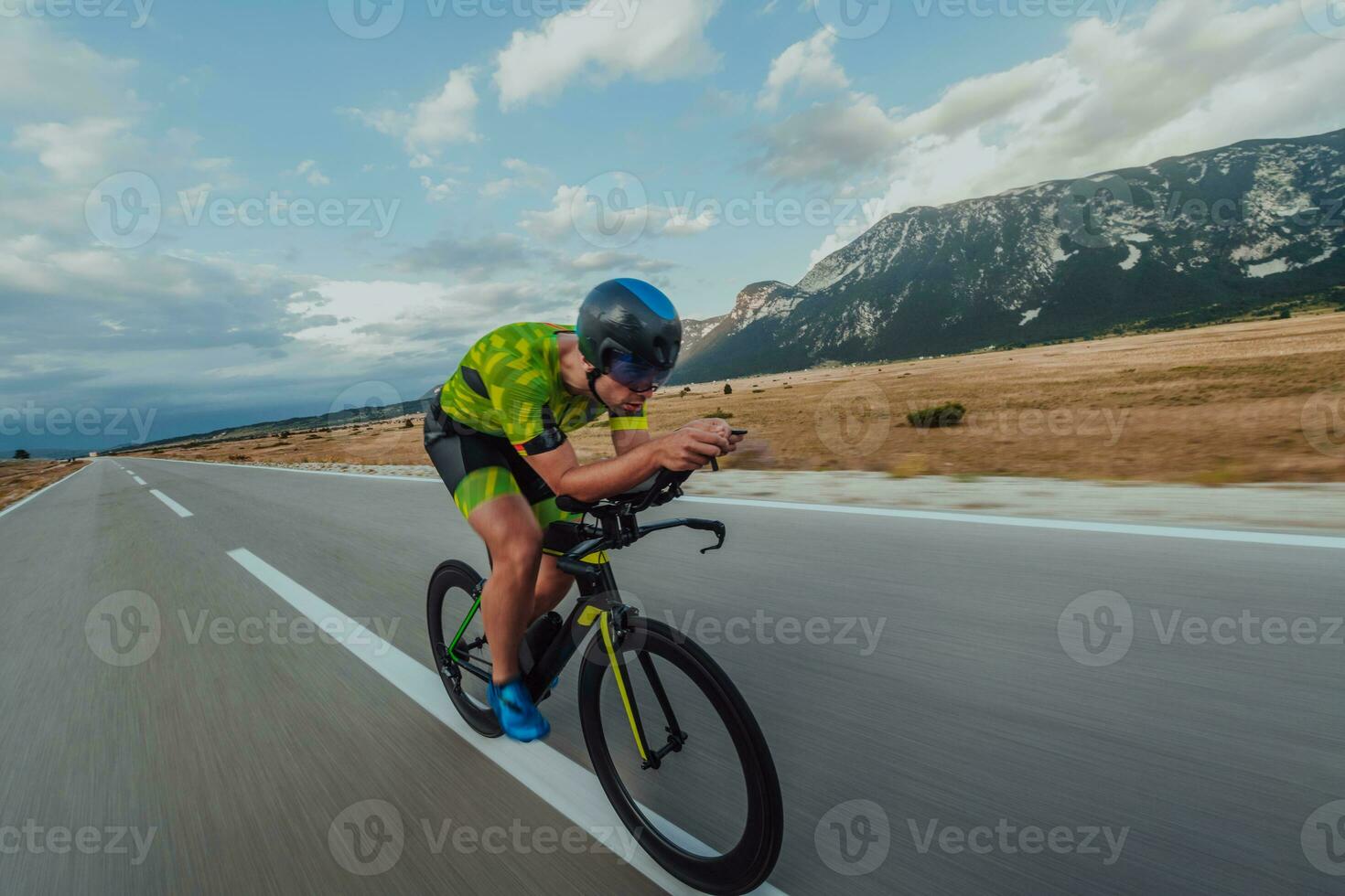 Full length portrait of an active triathlete in sportswear and with a protective helmet riding a bicycle. Selective focus photo