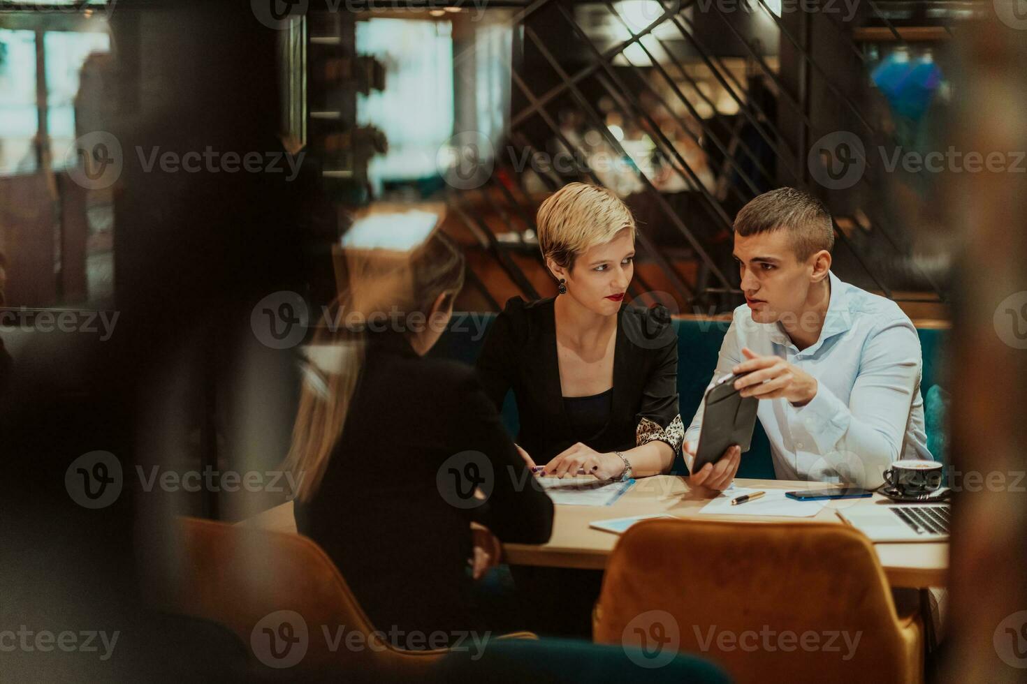 Happy businesspeople smiling cheerfully during a meeting in a coffee shop. Group of successful business professionals working as a team in a multicultural workplace. photo