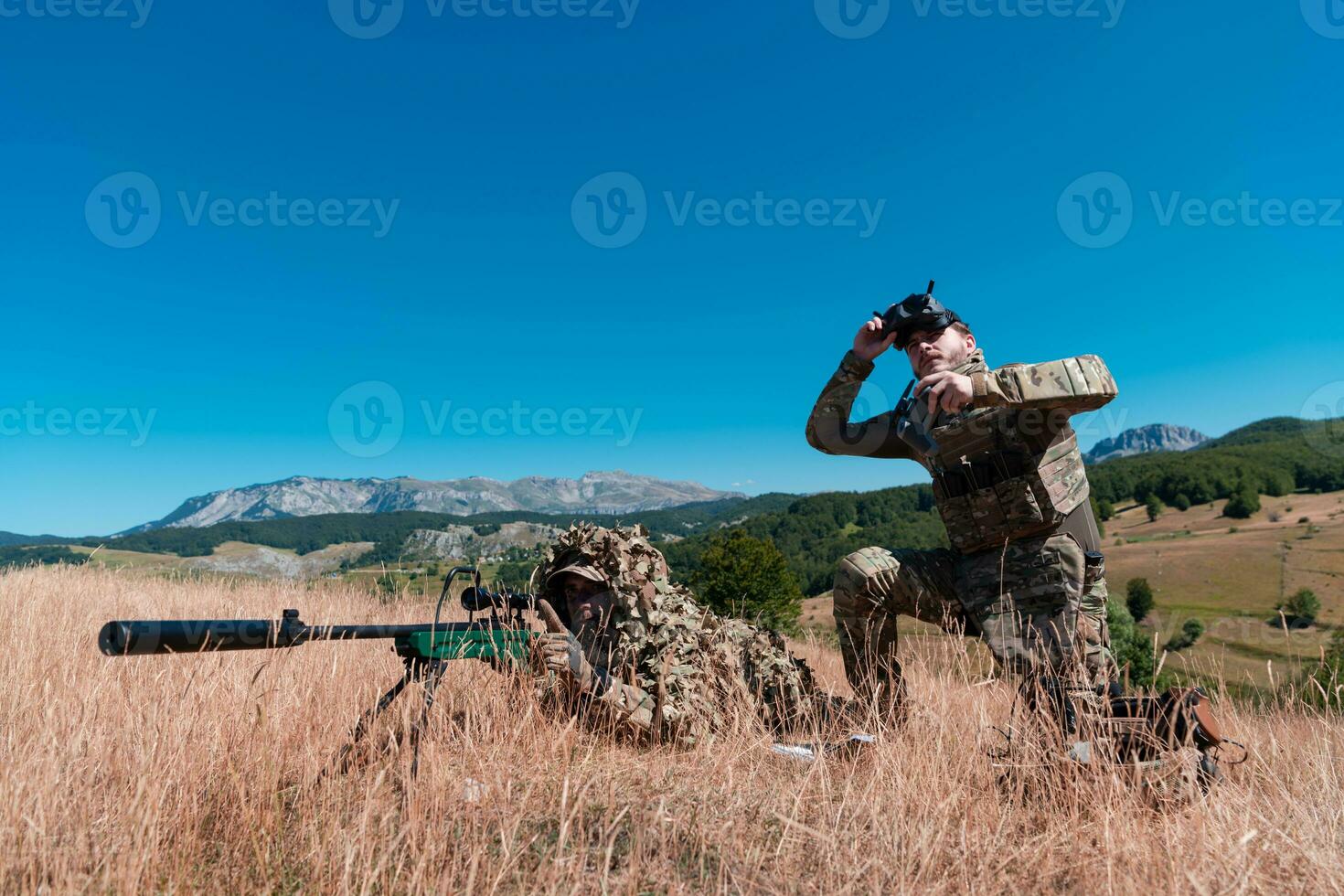 Sniper soldier assisted by an assistant to observe the area to be targeted with modern warfare tactical virtual reality goggles aerial drone military technology. photo