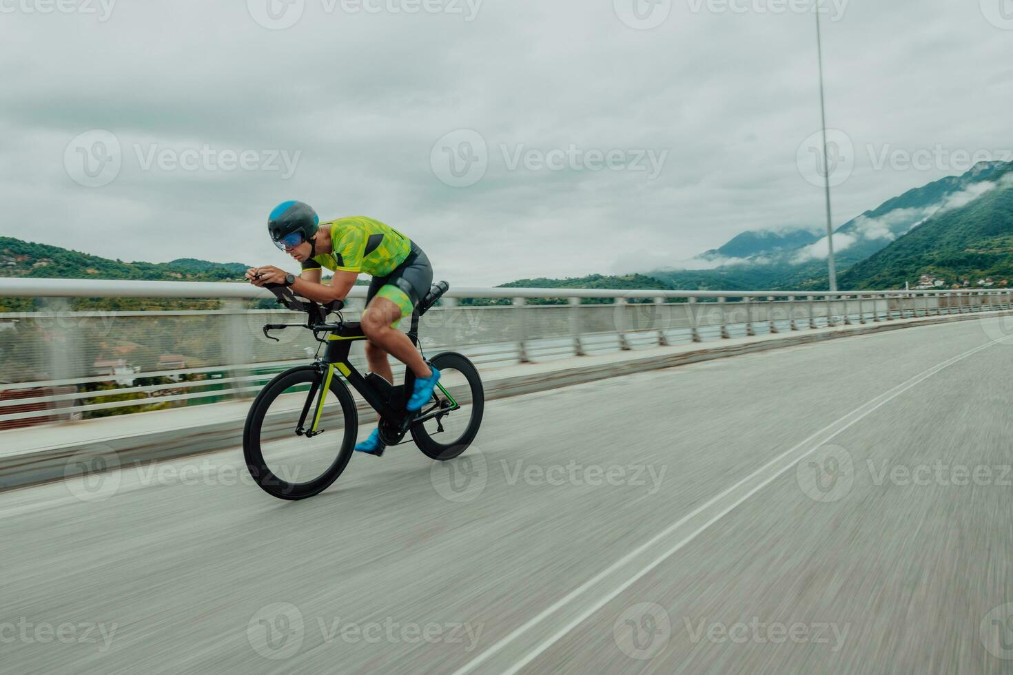 Full length portrait of an active triathlete in sportswear and with a protective helmet riding a bicycle. Selective focus photo