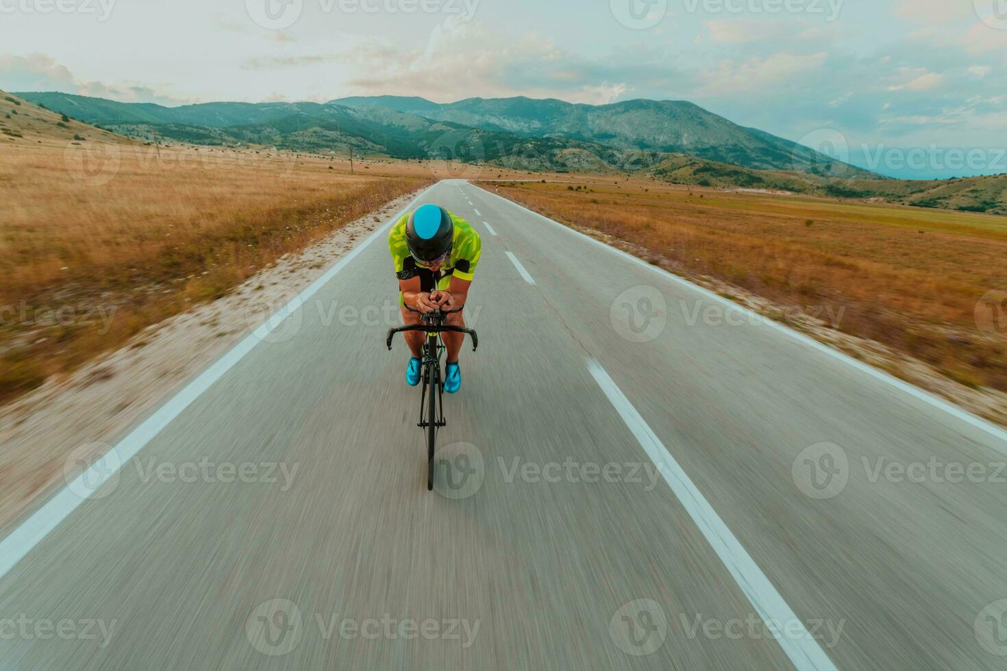 Full length portrait of an active triathlete in sportswear and with a protective helmet riding a bicycle. Selective focus photo