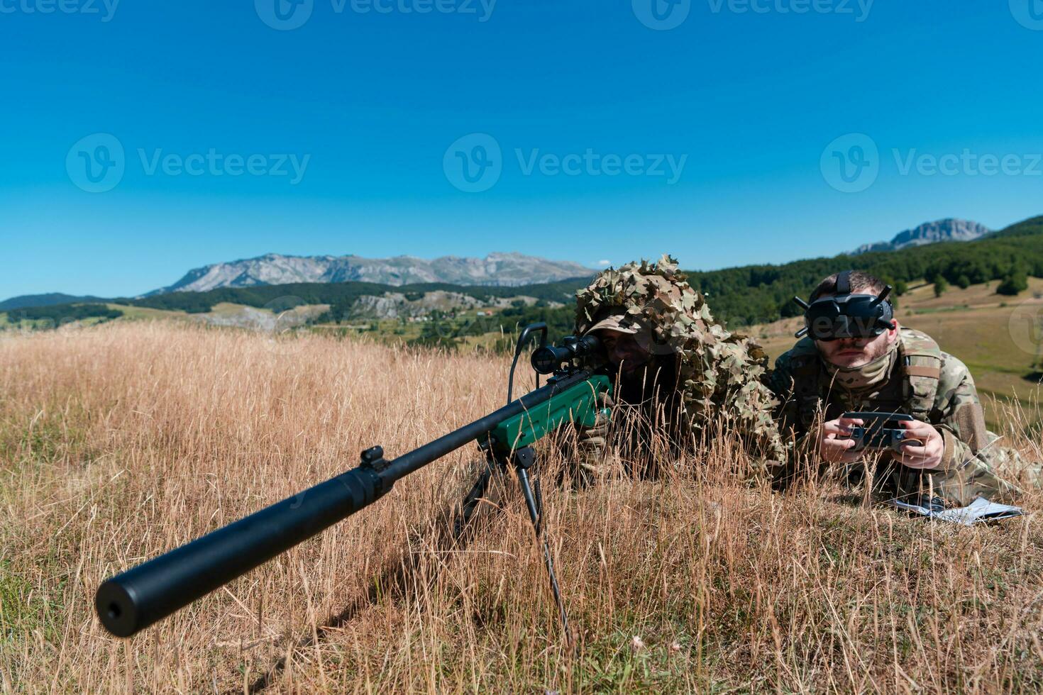 Sniper soldier assisted by an assistant to observe the area to be targeted with modern warfare tactical virtual reality goggles aerial drone military technology. photo