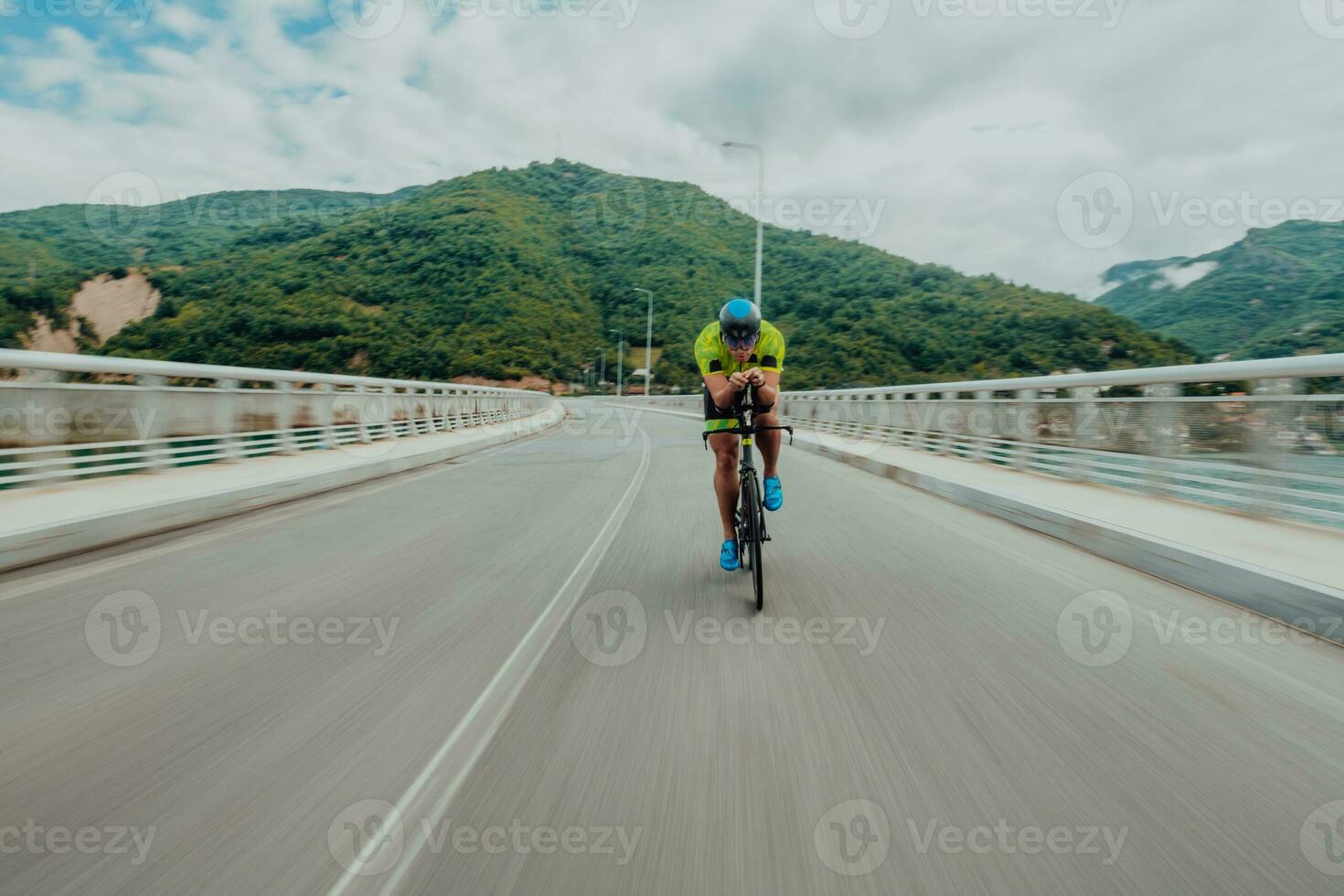 Full length portrait of an active triathlete in sportswear and with a protective helmet riding a bicycle. Selective focus photo