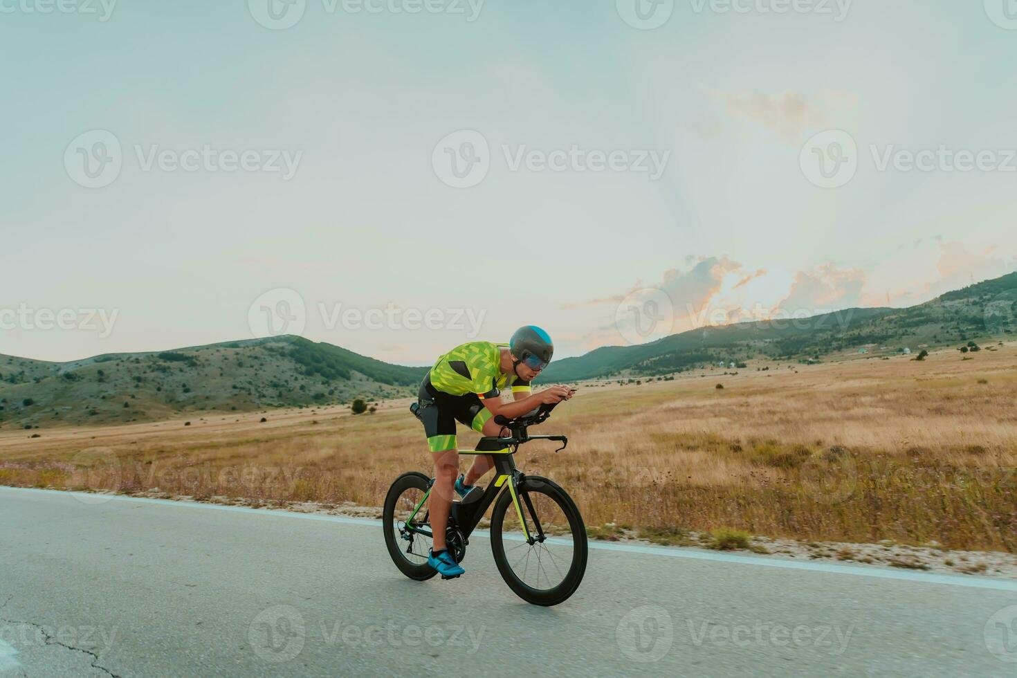 Full length portrait of an active triathlete in sportswear and with a protective helmet riding a bicycle. Selective focus photo