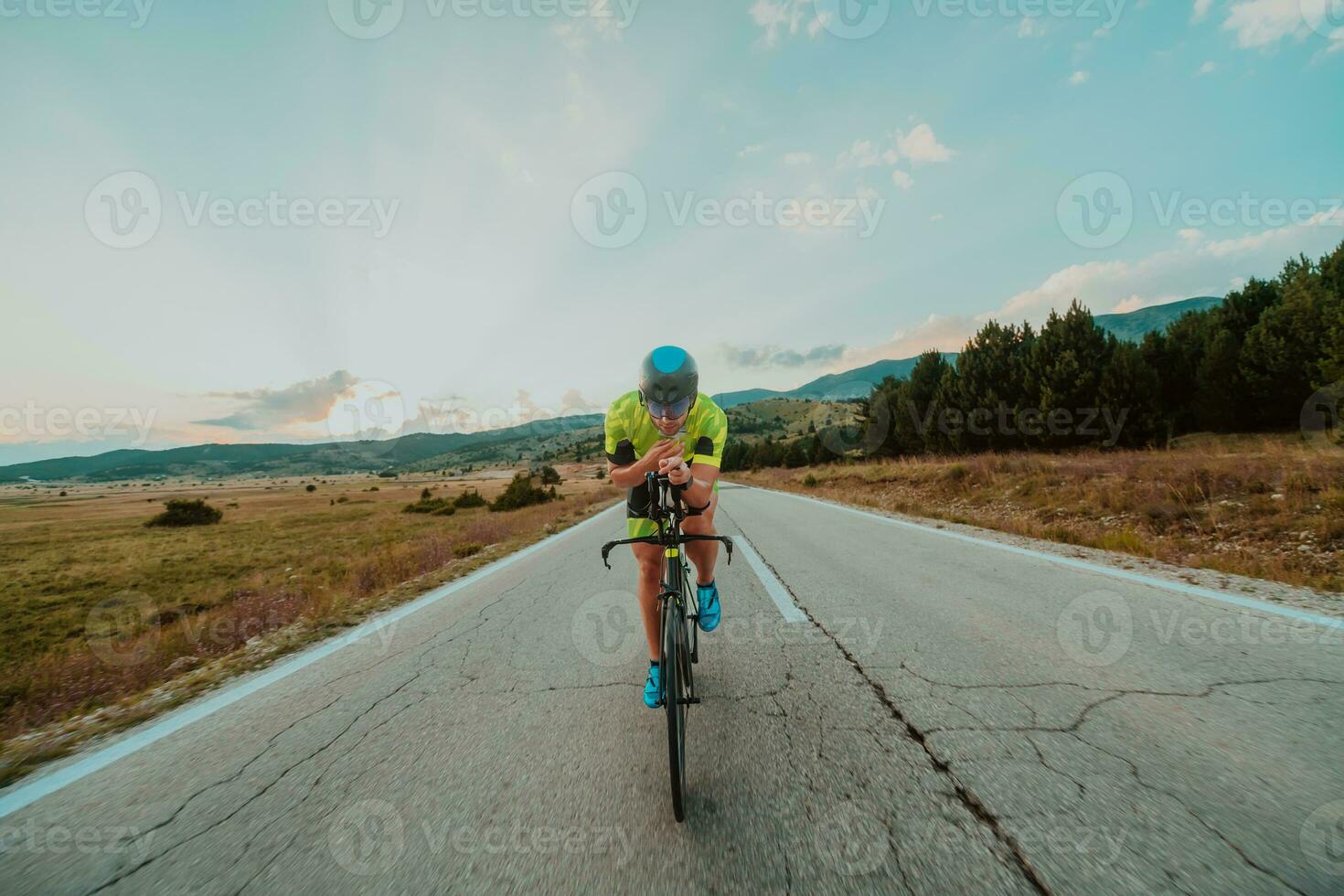 lleno longitud retrato de un activo triatleta en ropa de deporte y con un protector casco montando un bicicleta. selectivo atención foto