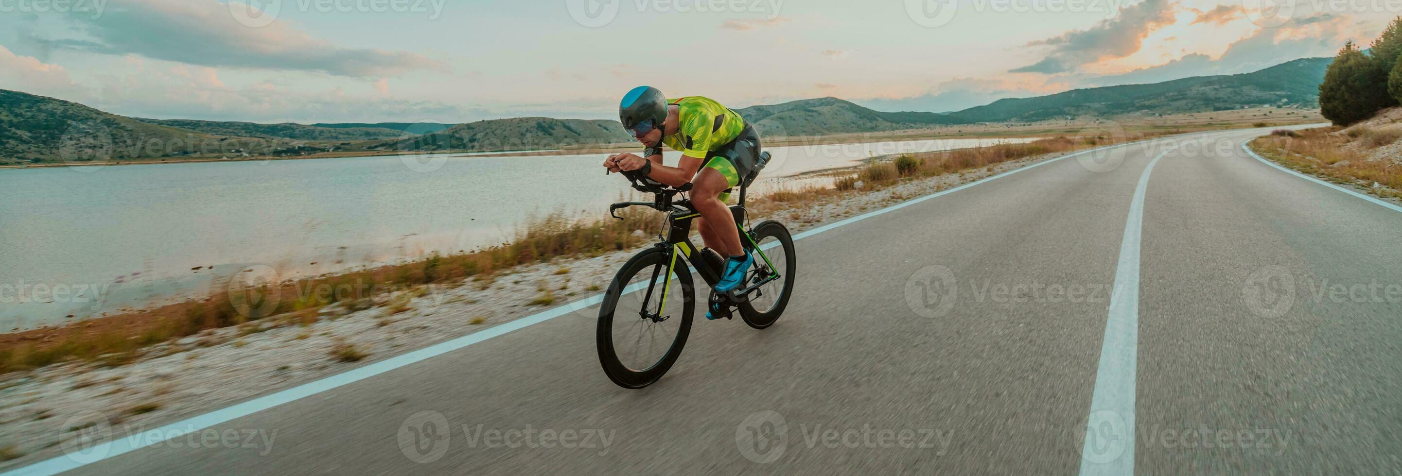 lleno longitud retrato de un activo triatleta en ropa de deporte y con un protector casco montando un bicicleta. selectivo atención foto