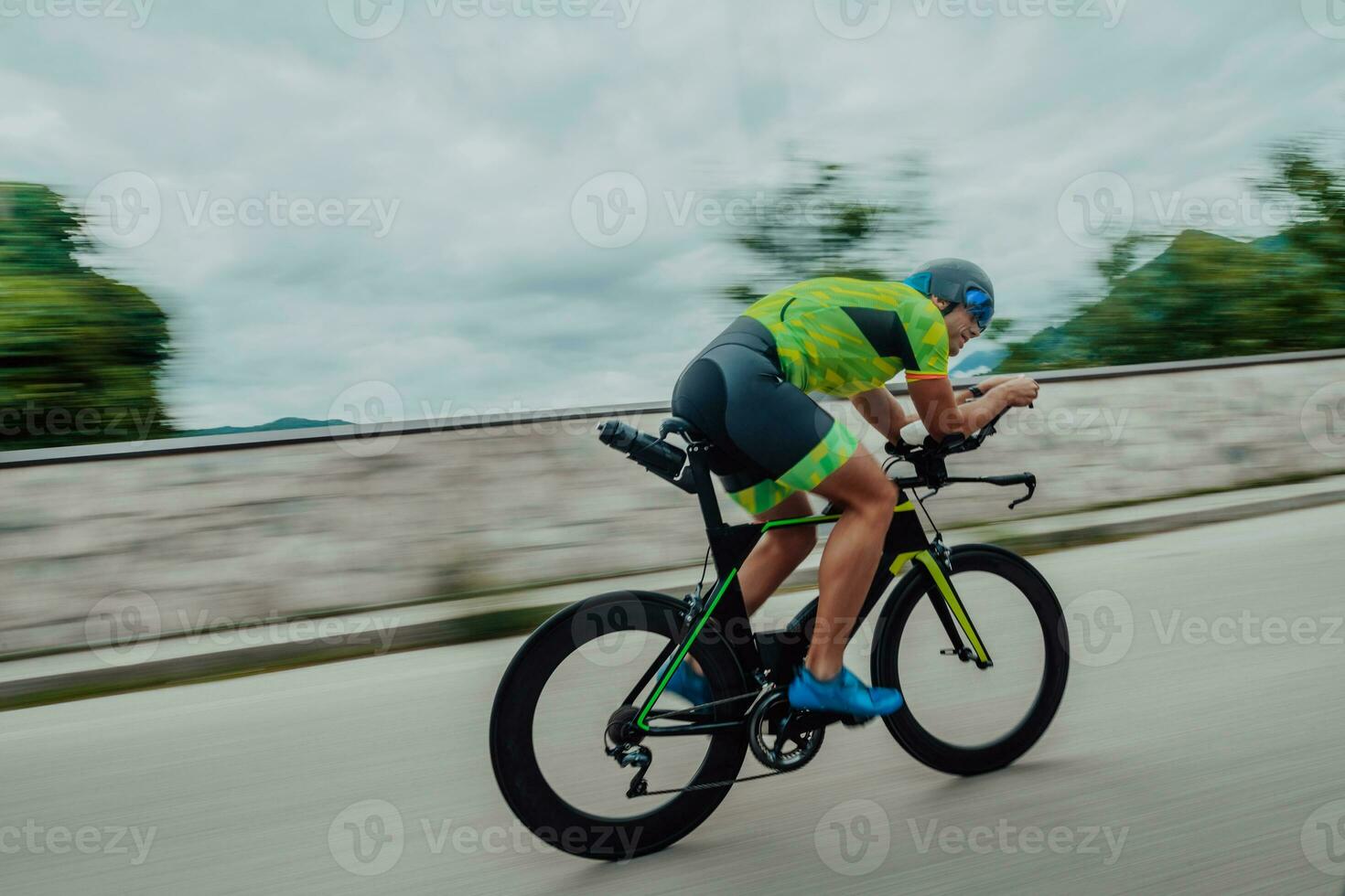 Full length portrait of an active triathlete in sportswear and with a protective helmet riding a bicycle. Selective focus photo