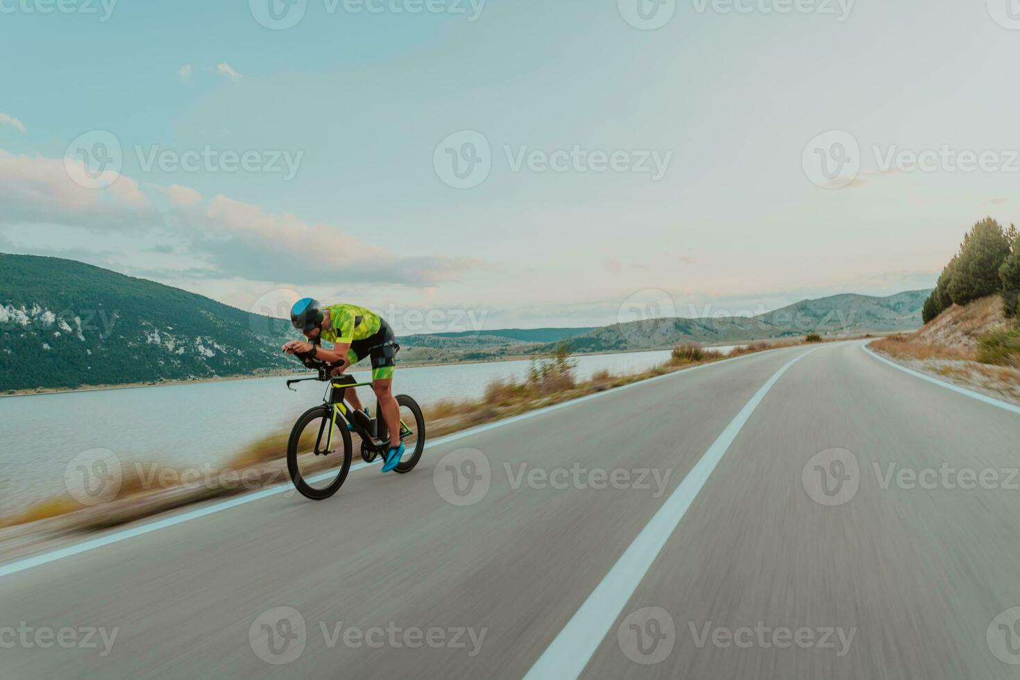 Full length portrait of an active triathlete in sportswear and with a protective helmet riding a bicycle. Selective focus photo