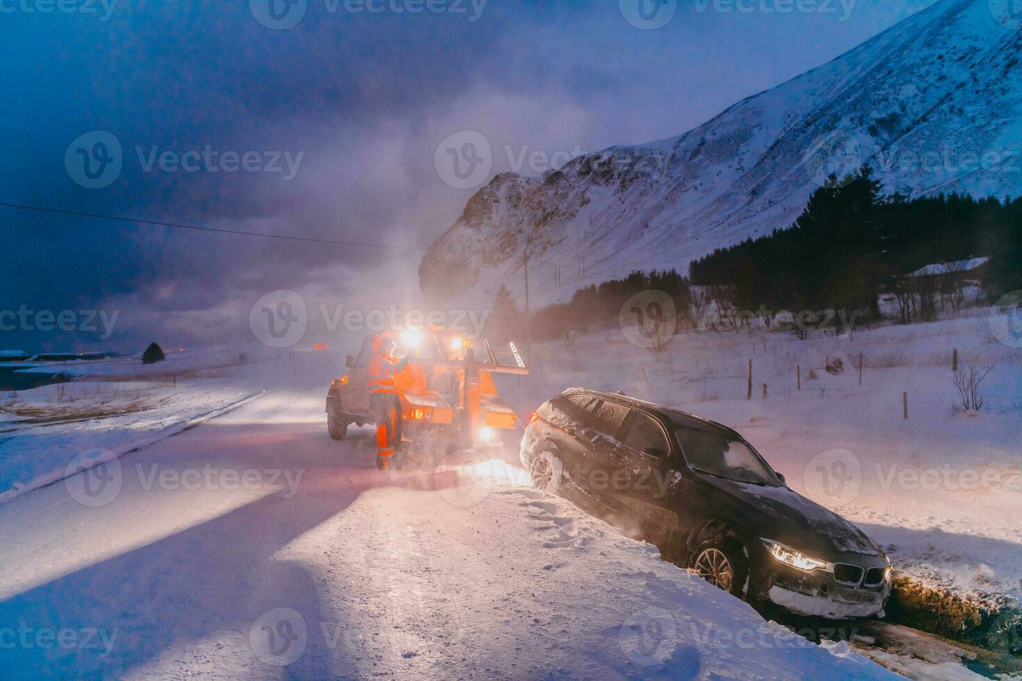 The roadside assistance service pulling the car out of the canal. An incident on a frozen Scandinavian road. photo