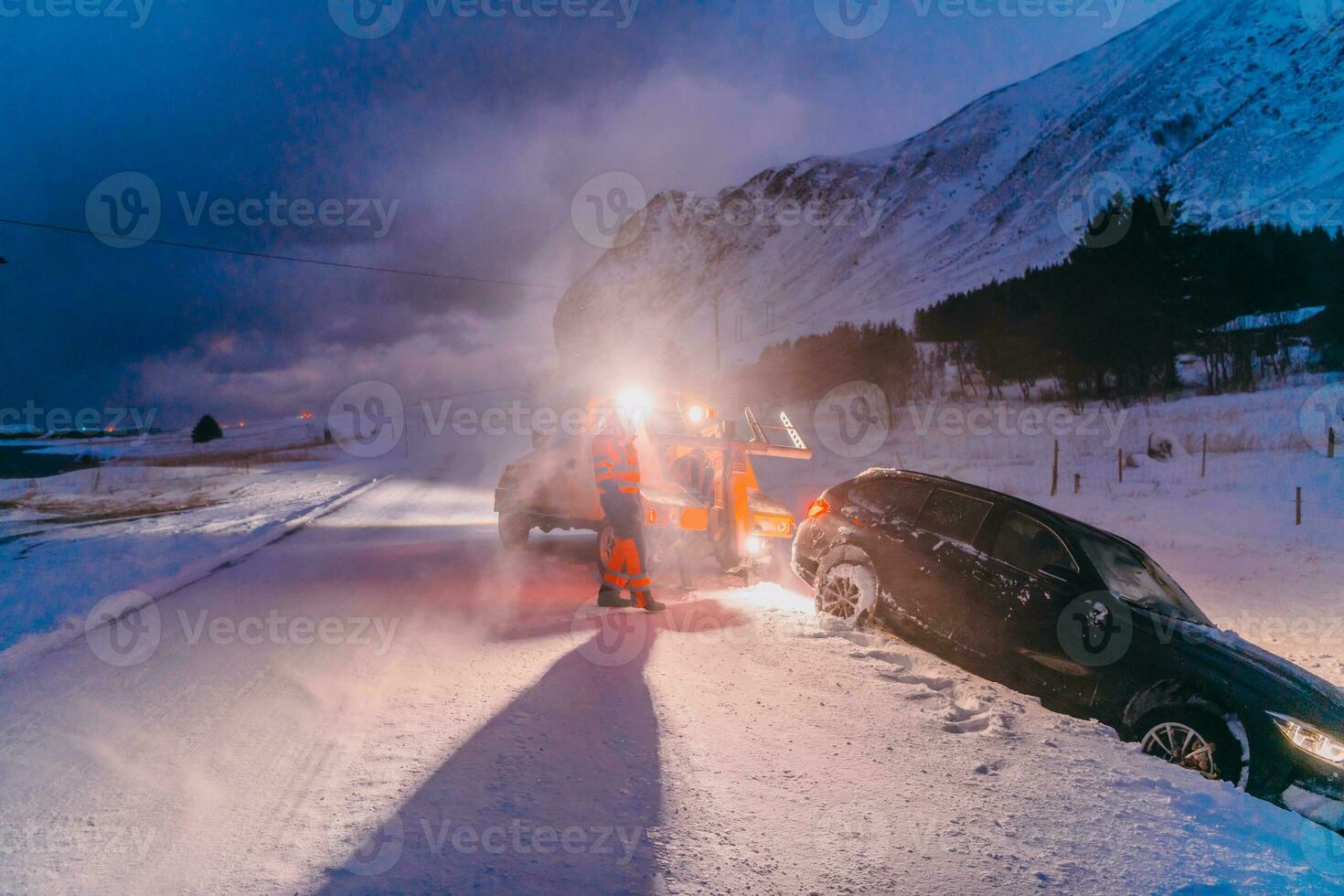 The roadside assistance service pulling the car out of the canal. An incident on a frozen Scandinavian road. photo