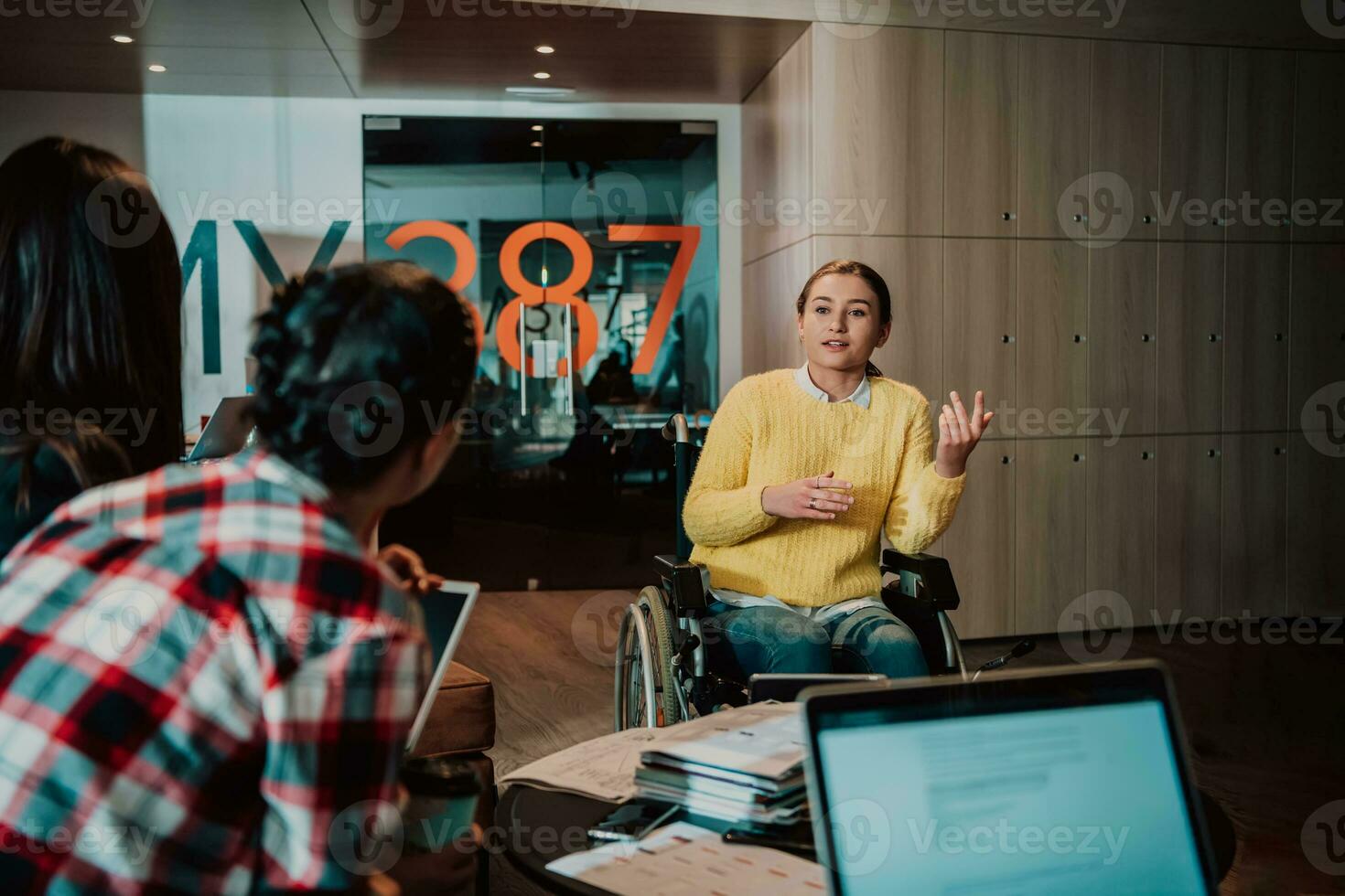 Businesswoman in wheelchair having business meeting with team at modern office. A group of young freelancers agree on new online business projects photo