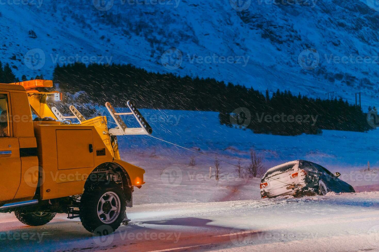 The roadside assistance service pulling the car out of the canal. An incident on a frozen Scandinavian road. photo