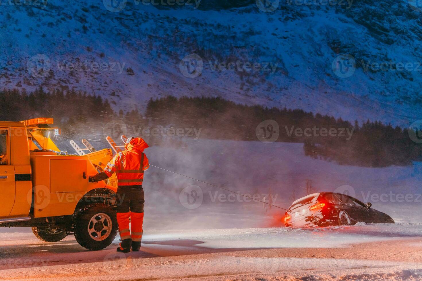The roadside assistance service pulling the car out of the canal. An incident on a frozen Scandinavian road. photo