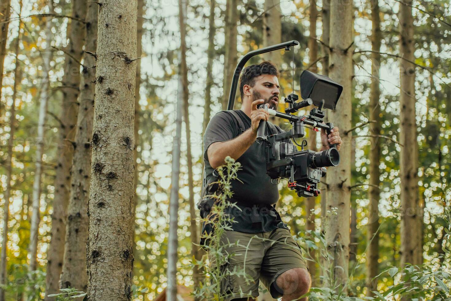 Videographer with Professional Movie Video Camera Gimbal Stabilizing Equipment Taking Action Shoot of Soldiers in Action in Forest photo
