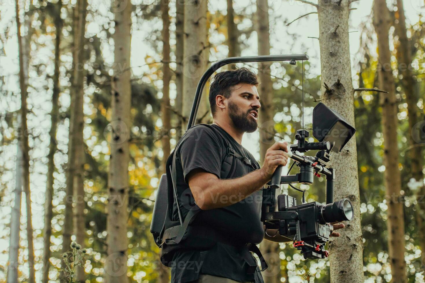 Videographer with Professional Movie Video Camera Gimbal Stabilizing Equipment Taking Action Shoot of Soldiers in Action in Forest photo