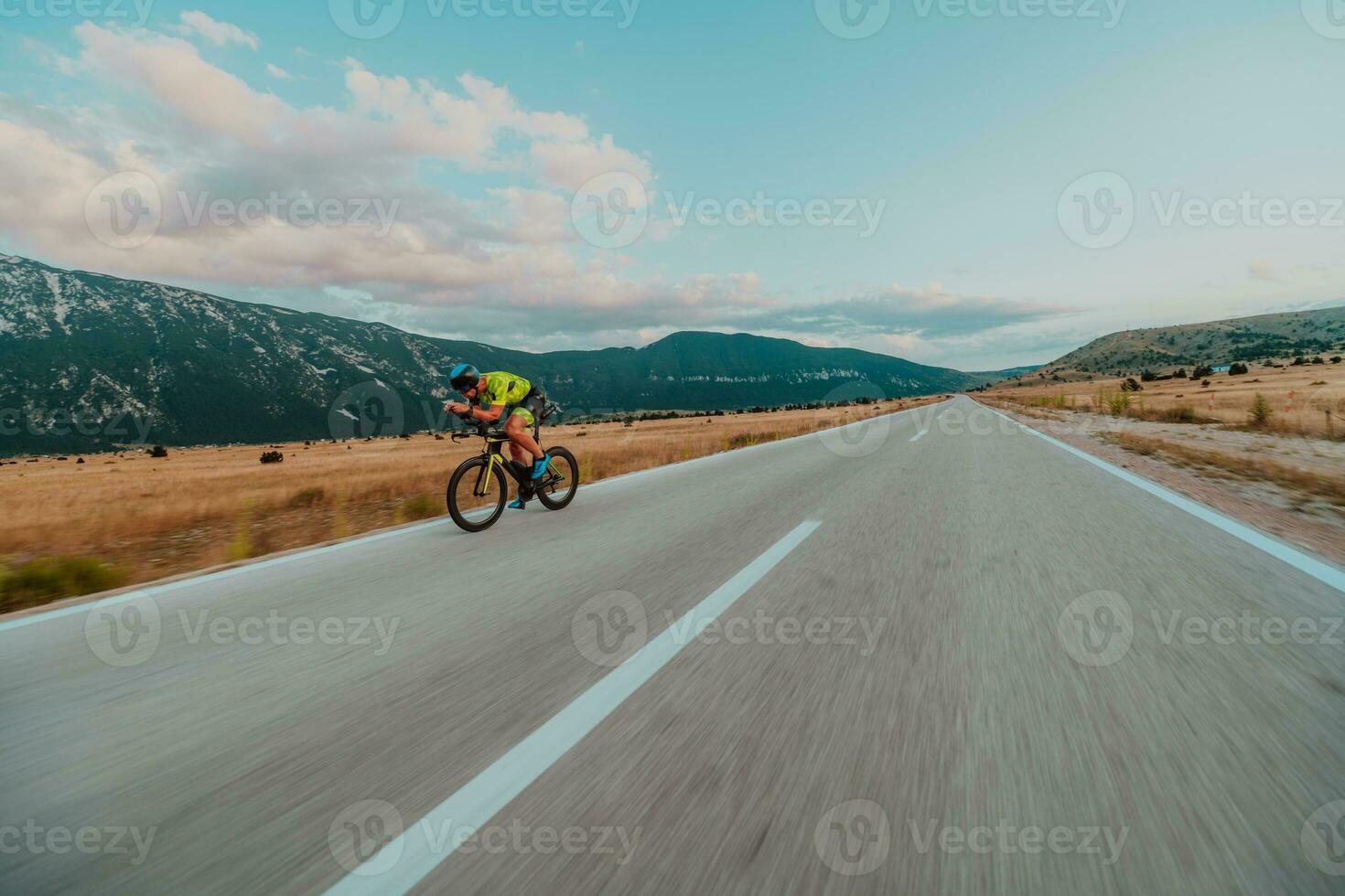 Full length portrait of an active triathlete in sportswear and with a protective helmet riding a bicycle. Selective focus photo