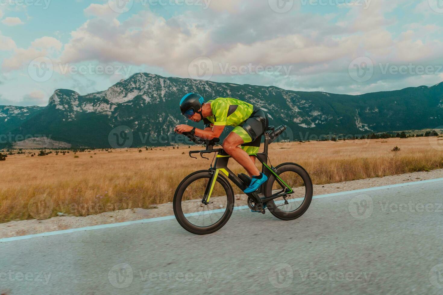 Full length portrait of an active triathlete in sportswear and with a protective helmet riding a bicycle. Selective focus photo