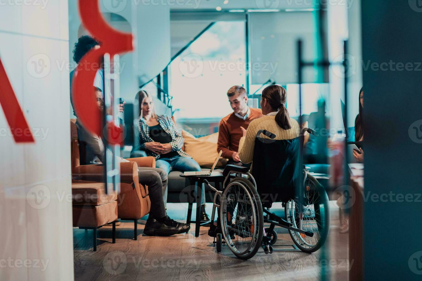 mujer de negocios en silla de ruedas teniendo negocio reunión con equipo a moderno oficina. un grupo de joven autónomos de acuerdo en nuevo en línea negocio proyectos foto