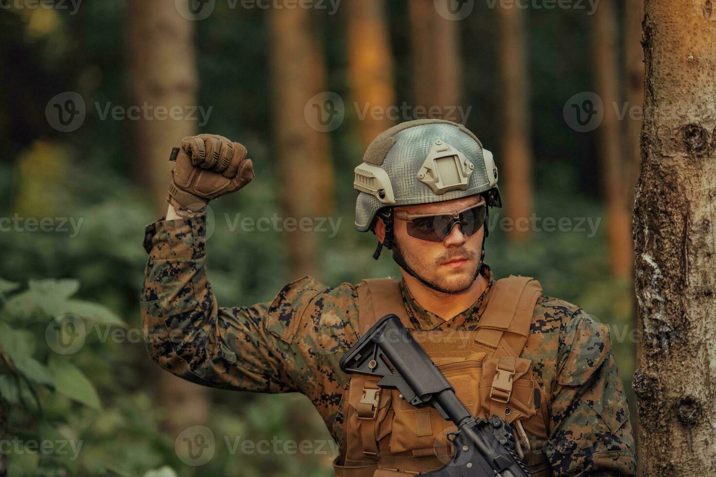 Modern warfare soldier officer is showing tactical hand signals to silently give orders and alers for squad team forest enviroment photo