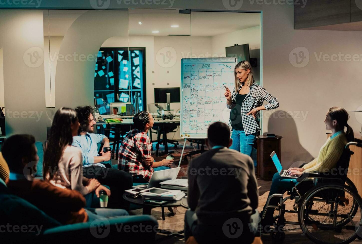 A pregnant businesswoman leads a creative meeting of a diverse business team in a modern coworking photo