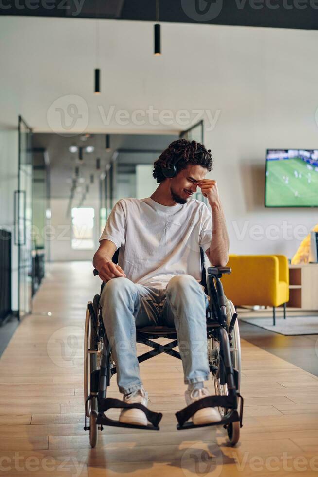 A sad businessman in a wheelchair occupies a hallway within a modern startup coworking center, embodying inclusivity and determination in the business environment photo