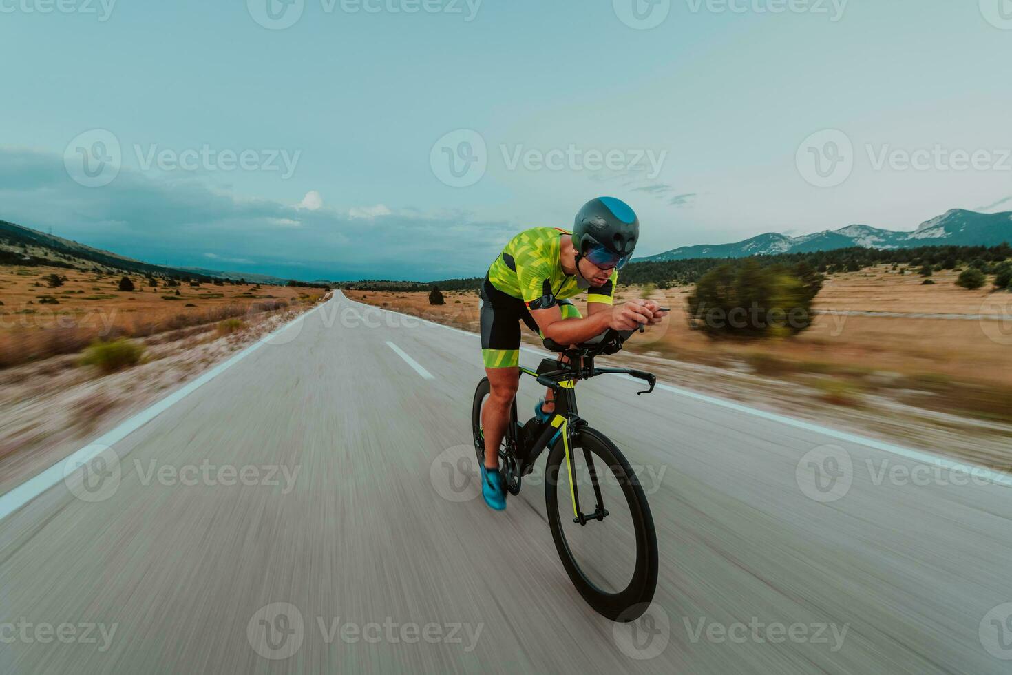 lleno longitud retrato de un activo triatleta en ropa de deporte y con un protector casco montando un bicicleta. selectivo atención foto