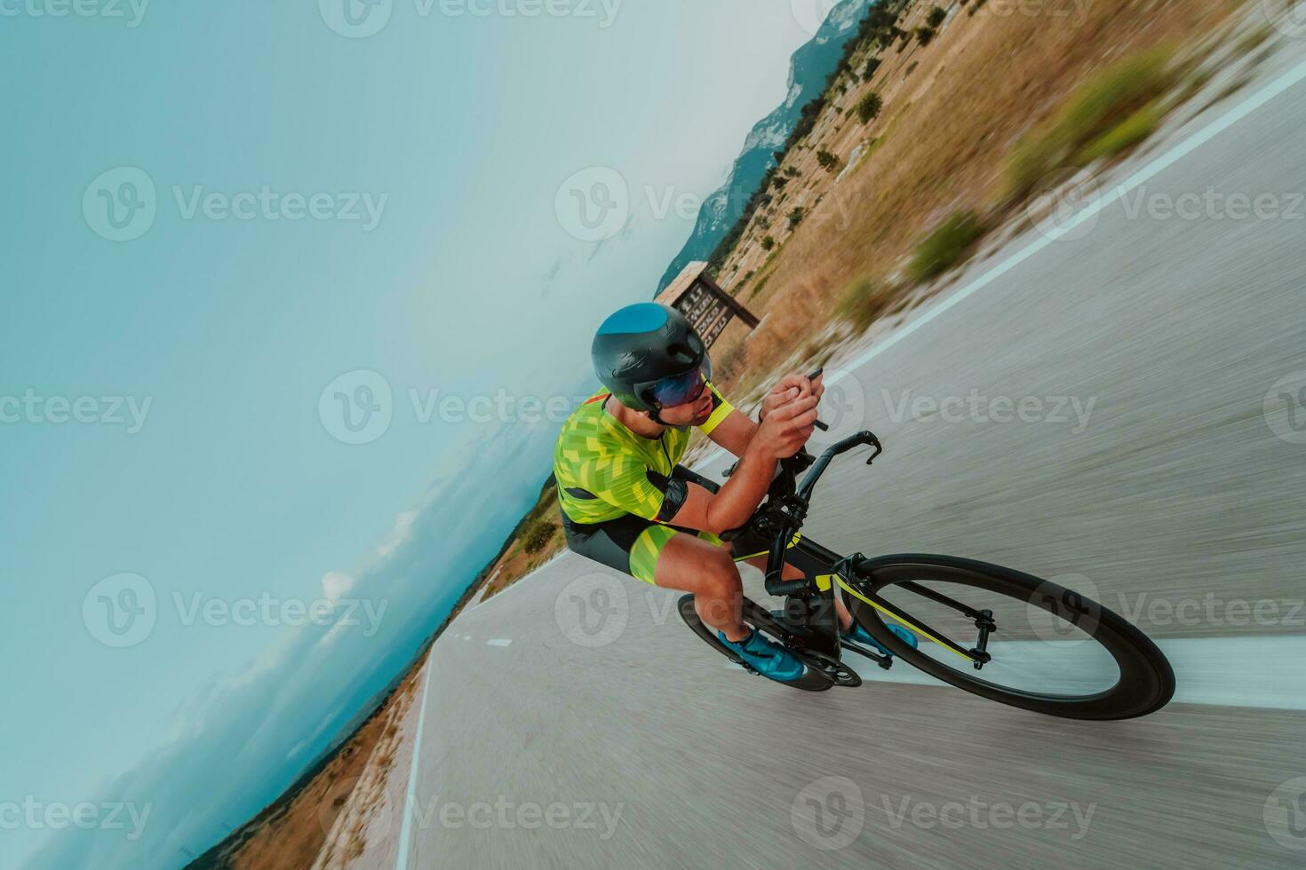 Full length portrait of an active triathlete in sportswear and with a protective helmet riding a bicycle. Selective focus photo