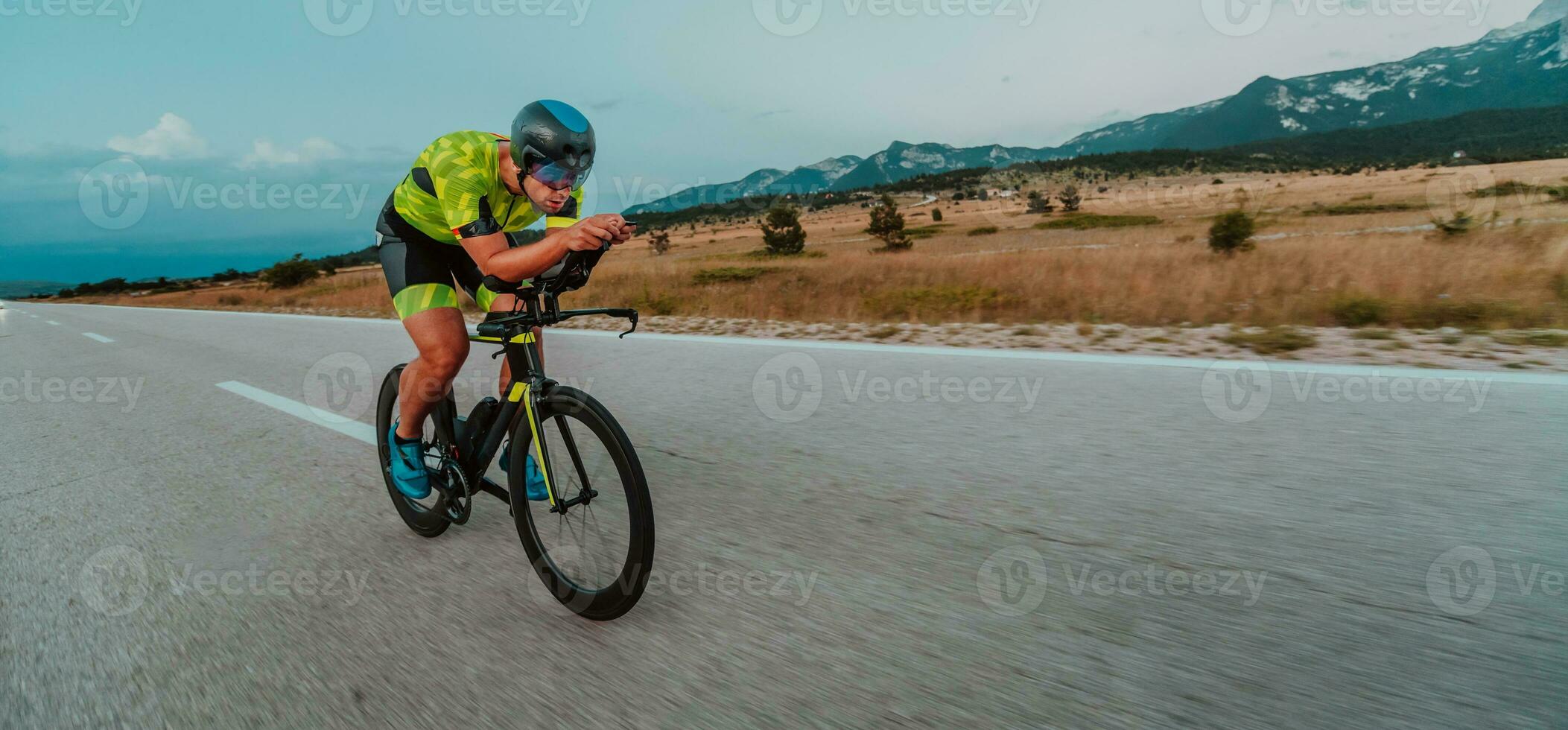 Full length portrait of an active triathlete in sportswear and with a protective helmet riding a bicycle. Selective focus photo