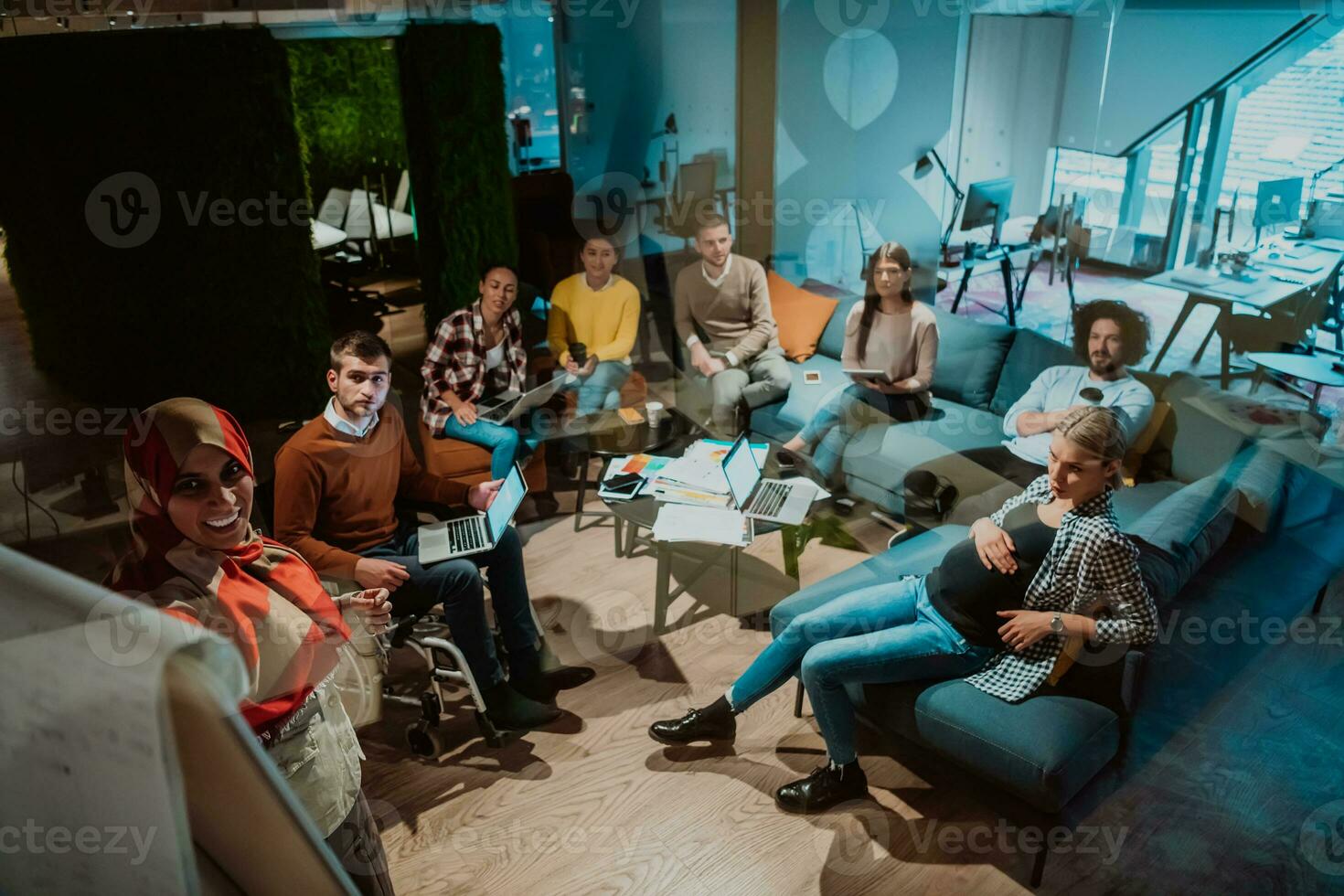 An older Muslim businesswoman presents a project to a young diverse team of people in a modern office photo