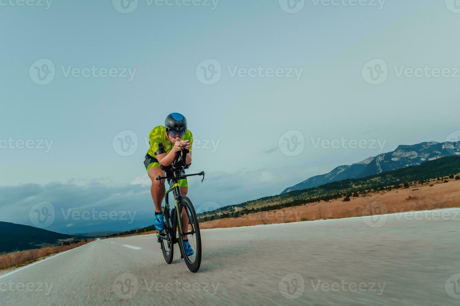 Full length portrait of an active triathlete in sportswear and with a protective helmet riding a bicycle. Selective focus photo