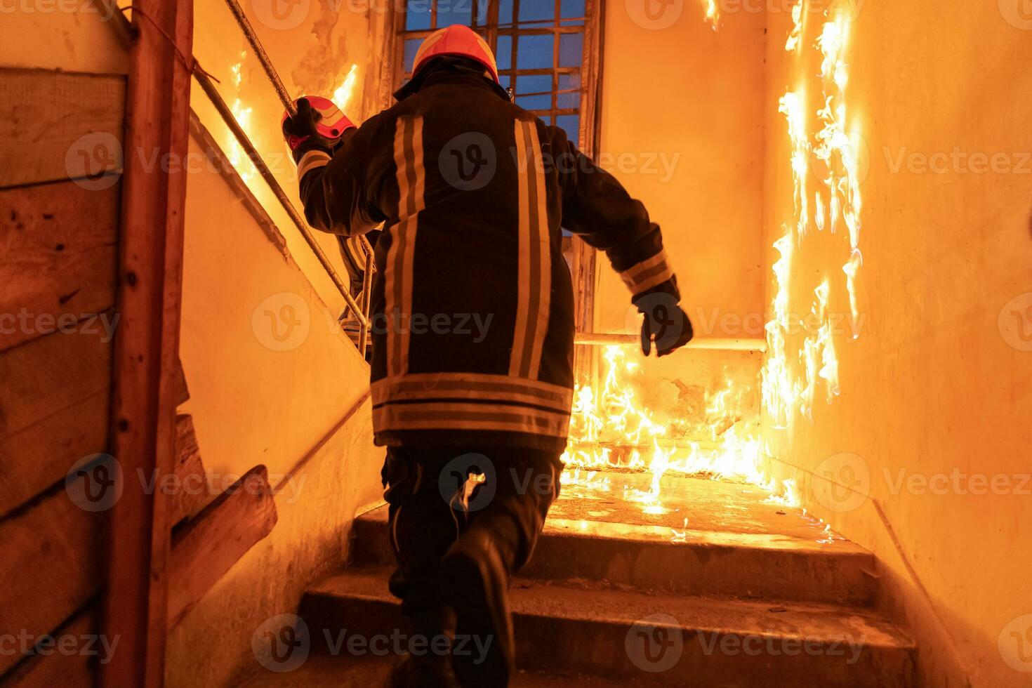 Brave Fireman going upstairs to save and rescue people in a Burning Building. Open fire and flame. photo