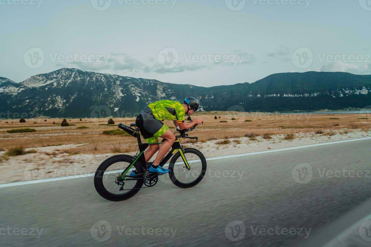 Full length portrait of an active triathlete in sportswear and with a protective helmet riding a bicycle. Selective focus photo