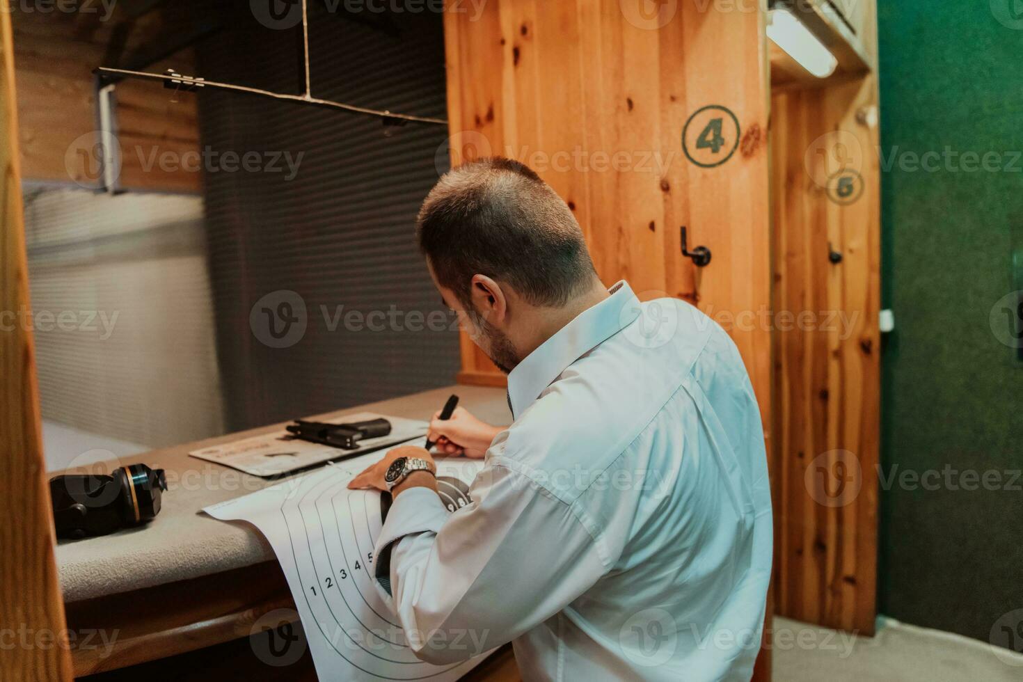 A man in a shooting range takes a picture and examines the results after shooting photo