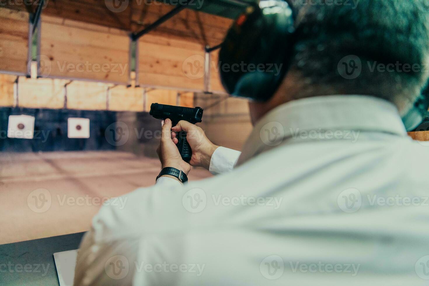 A man practices shooting a pistol in a shooting range while wearing protective headphones photo