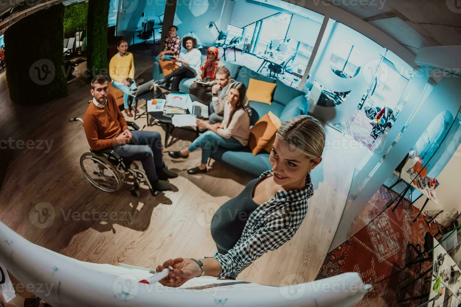 A pregnant businesswoman leads a creative meeting of a diverse business team in a modern coworking photo