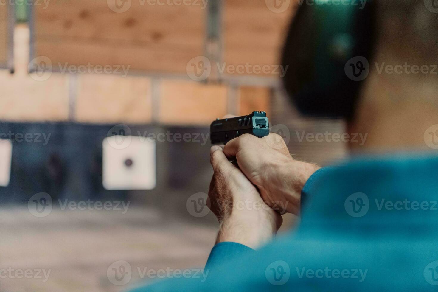 A man practices shooting a pistol in a shooting range while wearing protective headphones photo