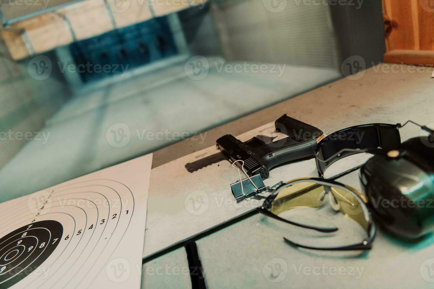 Shooting equipment in front of the target. Pistol, goggles and headphones on the table of a modern shooting range photo