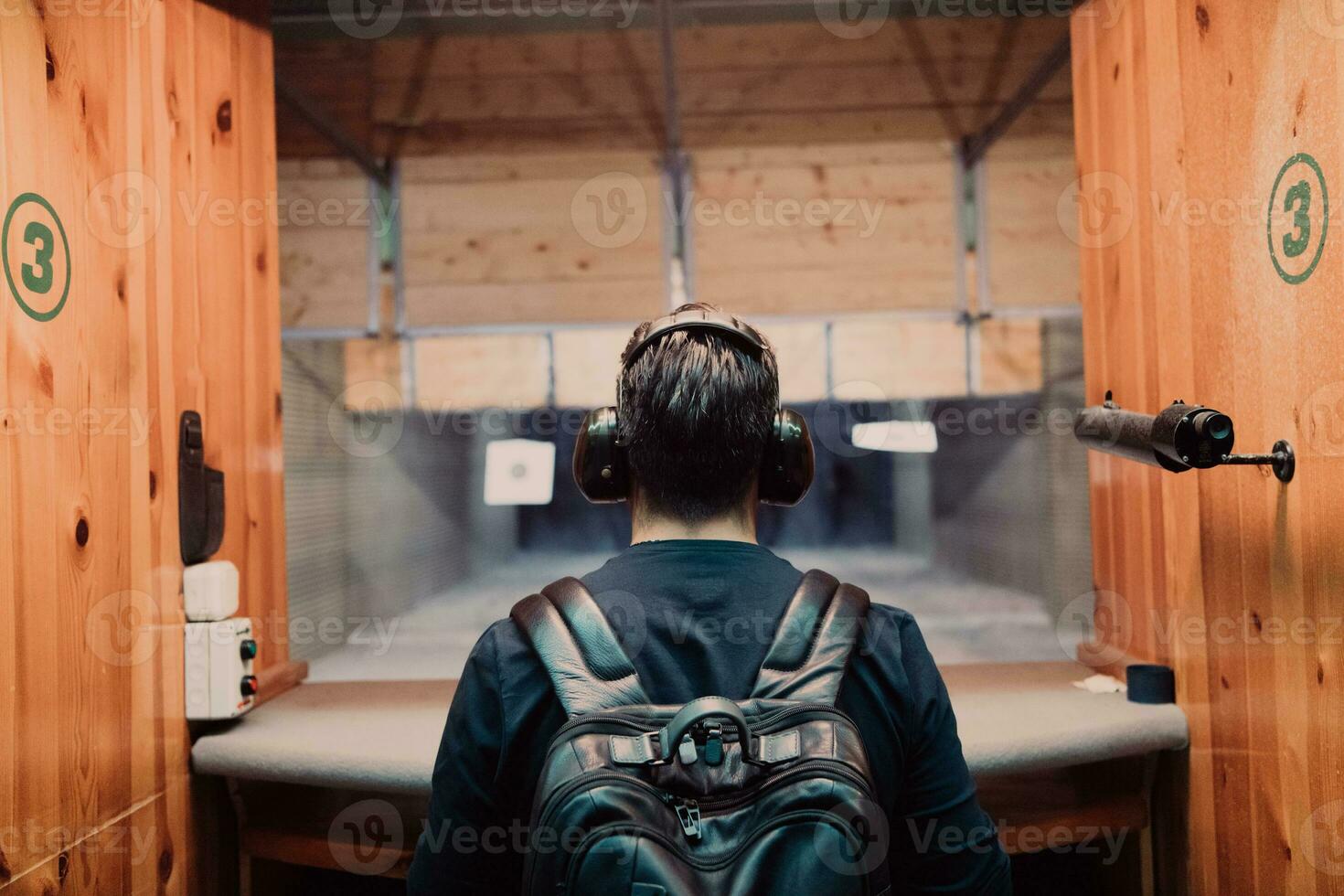 A man practices shooting a pistol in a shooting range while wearing protective headphones photo