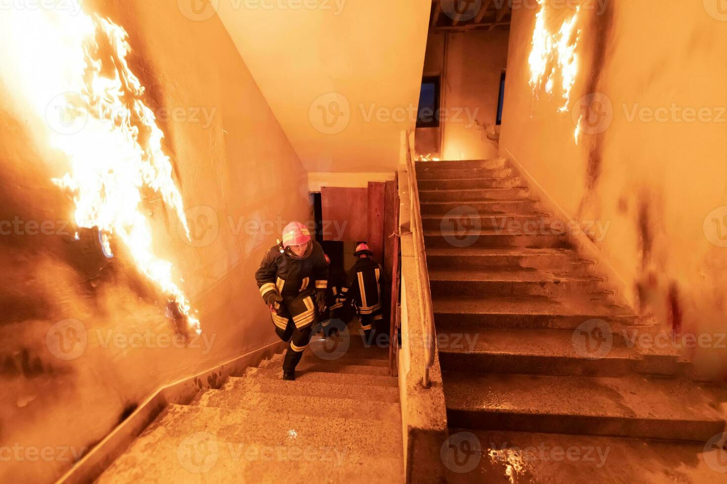 valiente bombero desciende escalera de un ardiente edificio y sostiene salvado niña en su brazos. abierto fuego y uno bombero en el antecedentes. foto