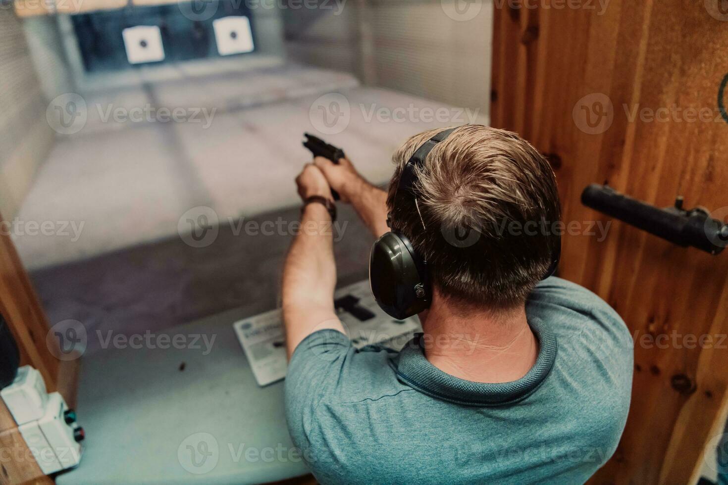 A man practices shooting a pistol in a shooting range while wearing protective headphones photo