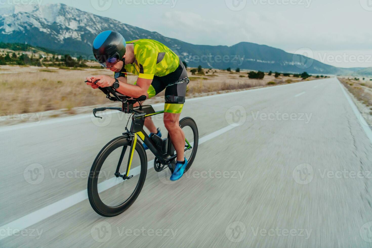 Full length portrait of an active triathlete in sportswear and with a protective helmet riding a bicycle. Selective focus photo