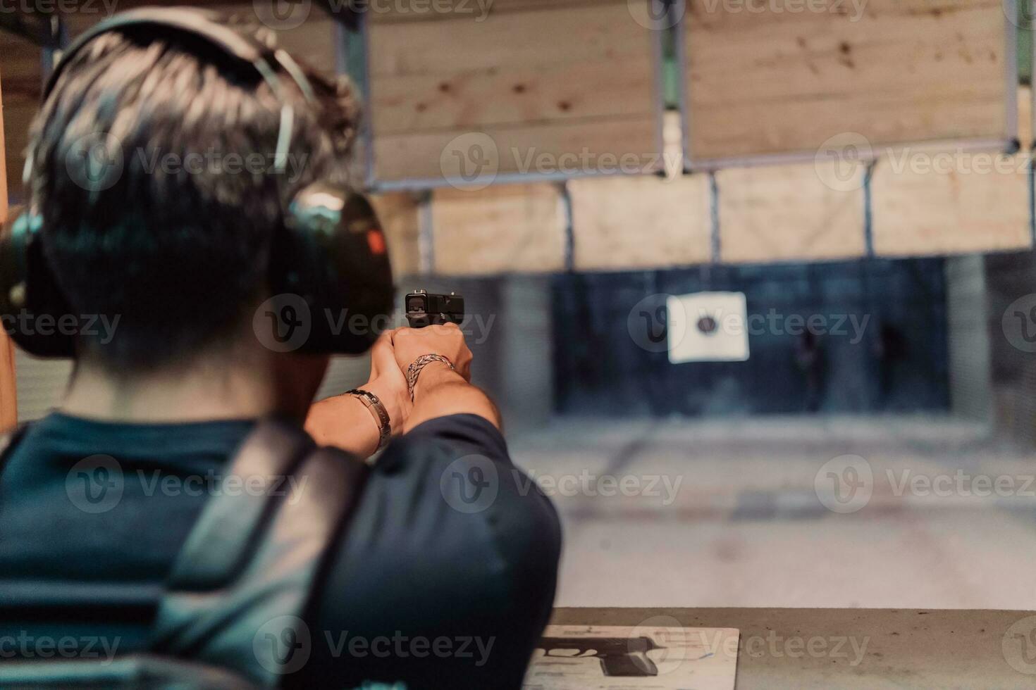 A man practices shooting a pistol in a shooting range while wearing protective headphones photo