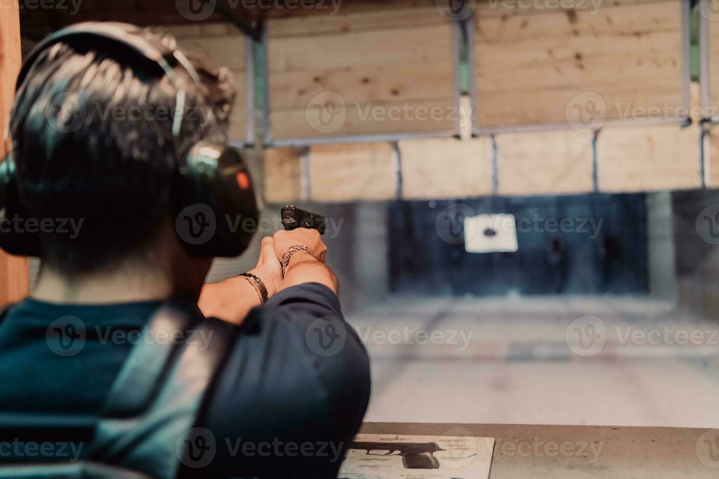 A man practices shooting a pistol in a shooting range while wearing protective headphones photo