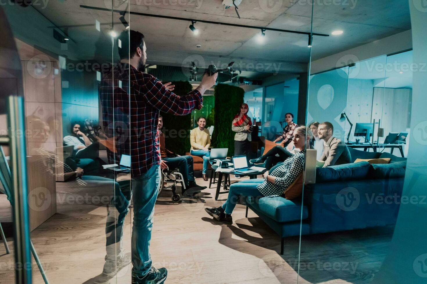 A bearded man in a modern office explaining to his young diverse team how a drone working photo