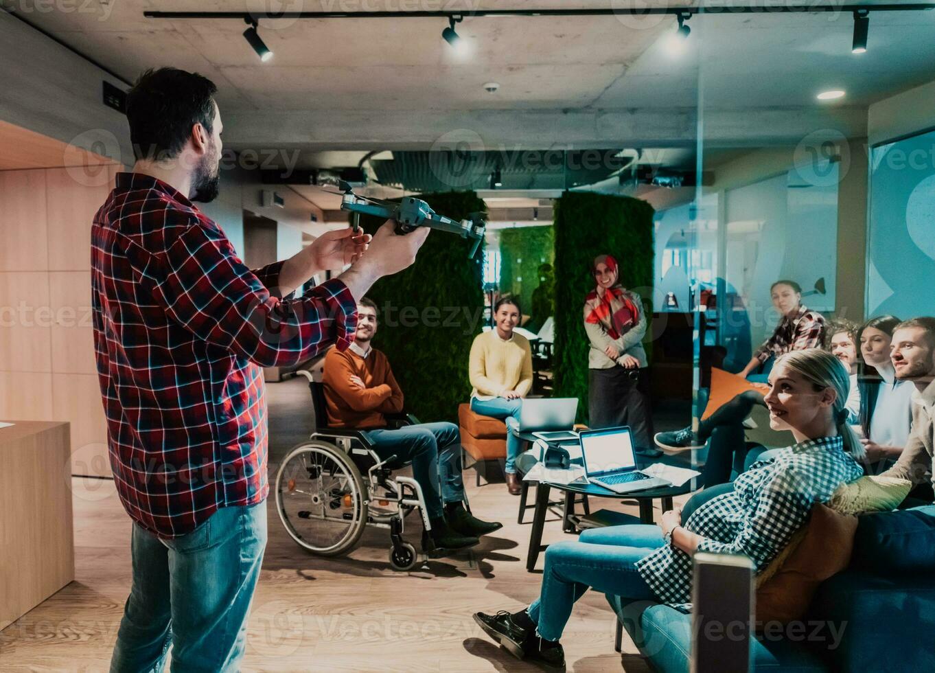 un barbado hombre en un moderno oficina explicando a su joven diverso equipo cómo un zumbido trabajando foto