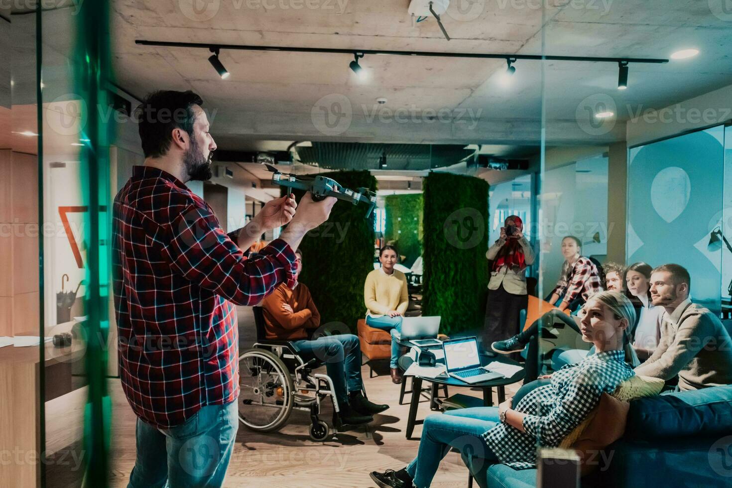 A bearded man in a modern office explaining to his young diverse team how a drone working photo